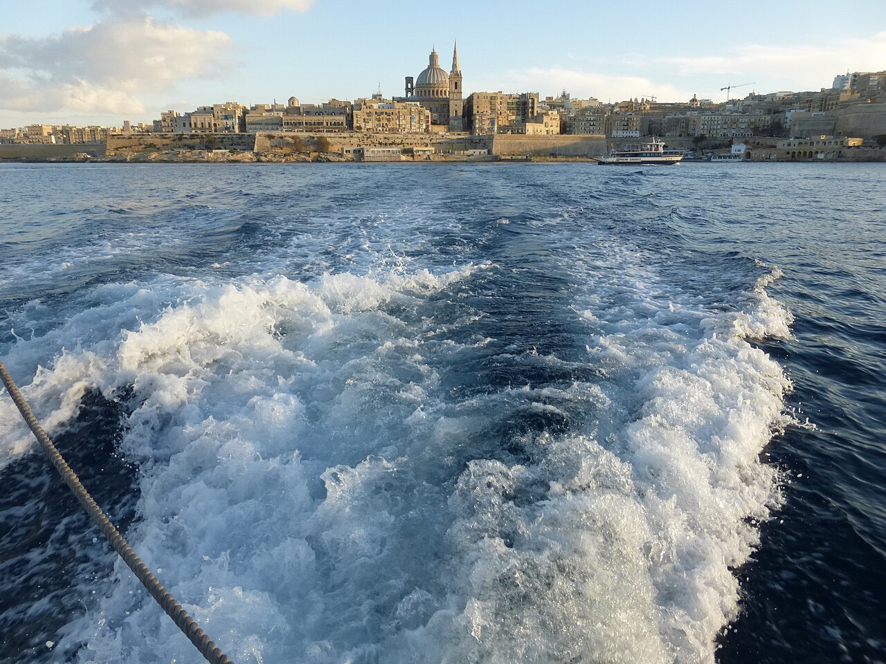 Wake of the Sliema to Valletta ferry with the Valletta skyline in…