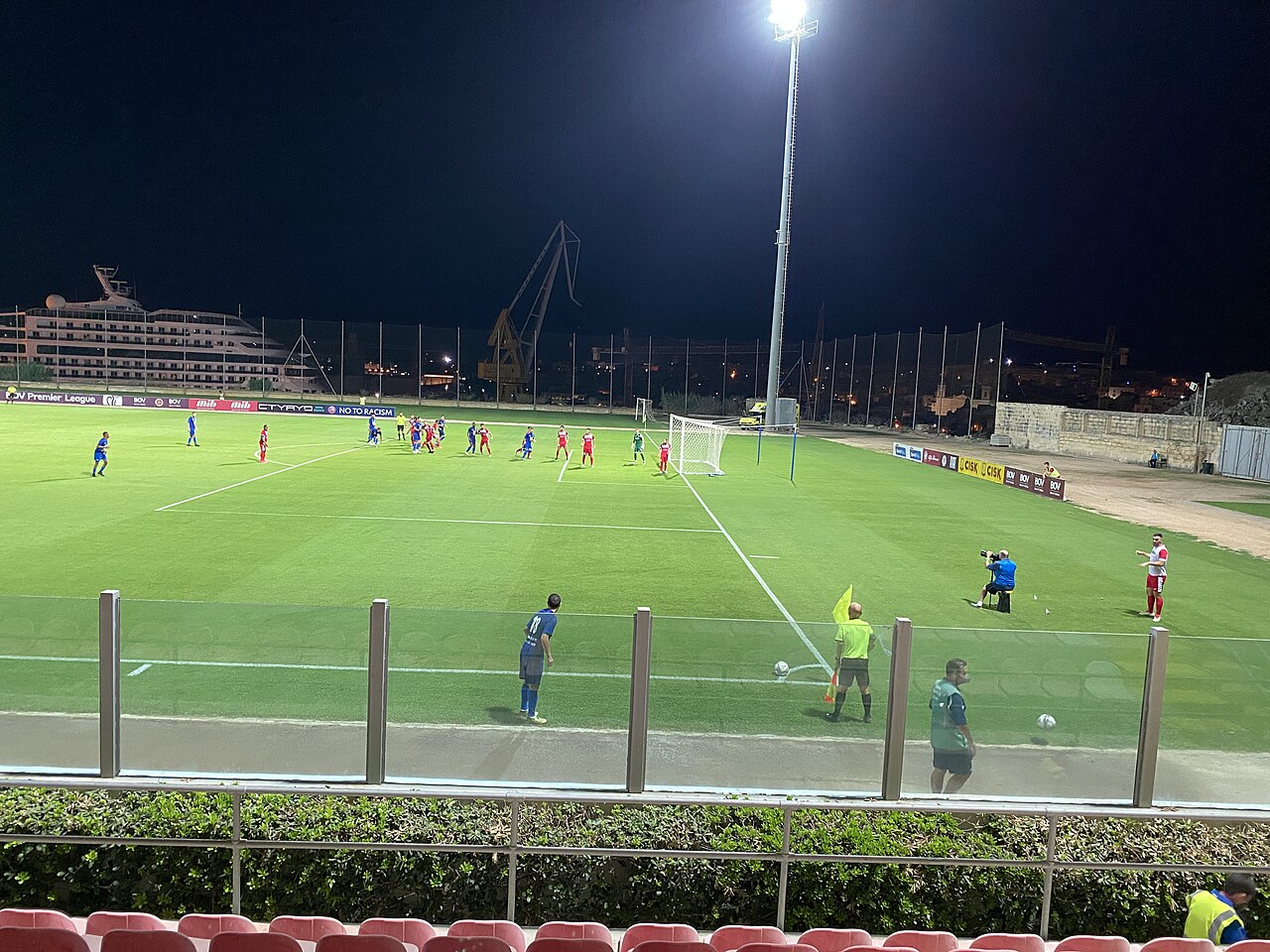 Floodlit football pitch during a Sliema Wanderers match, with a…