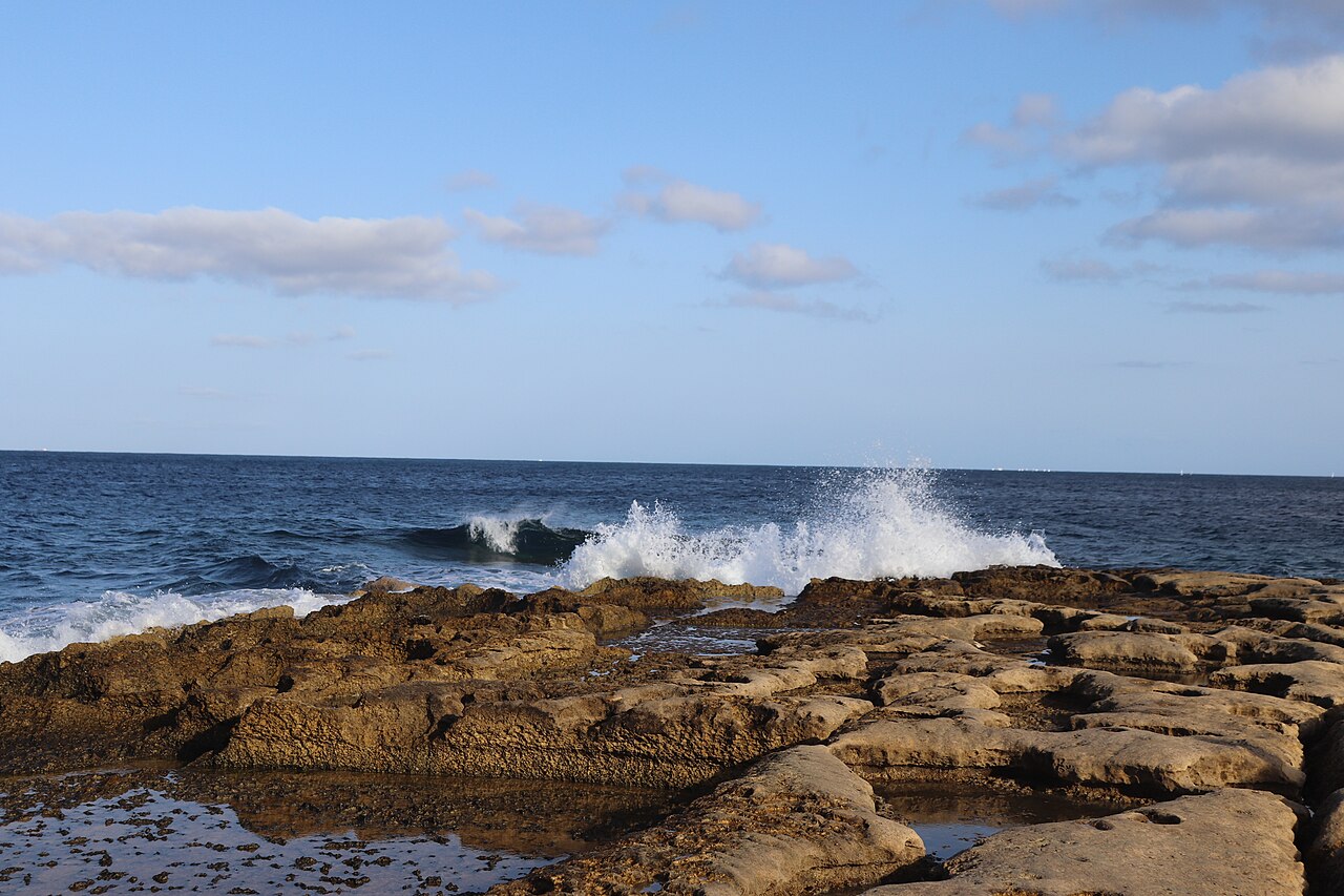 Waves crashing onto the flat rocky coast at Sliema