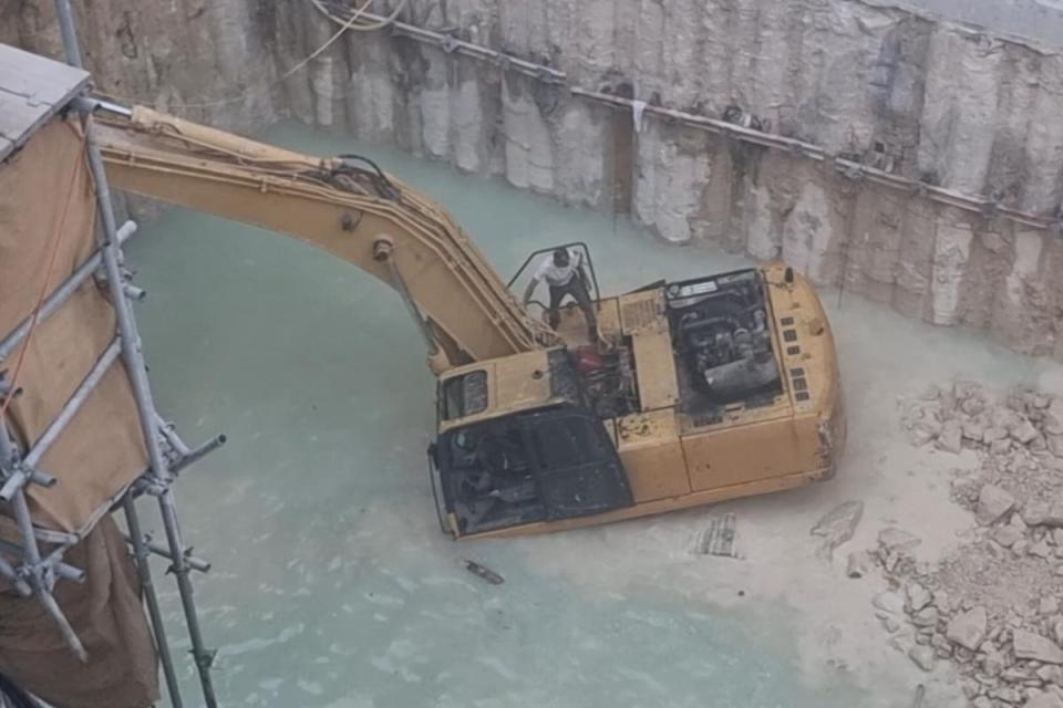 Worker atop submerged excavator as Sliema hotel site floods The Strand